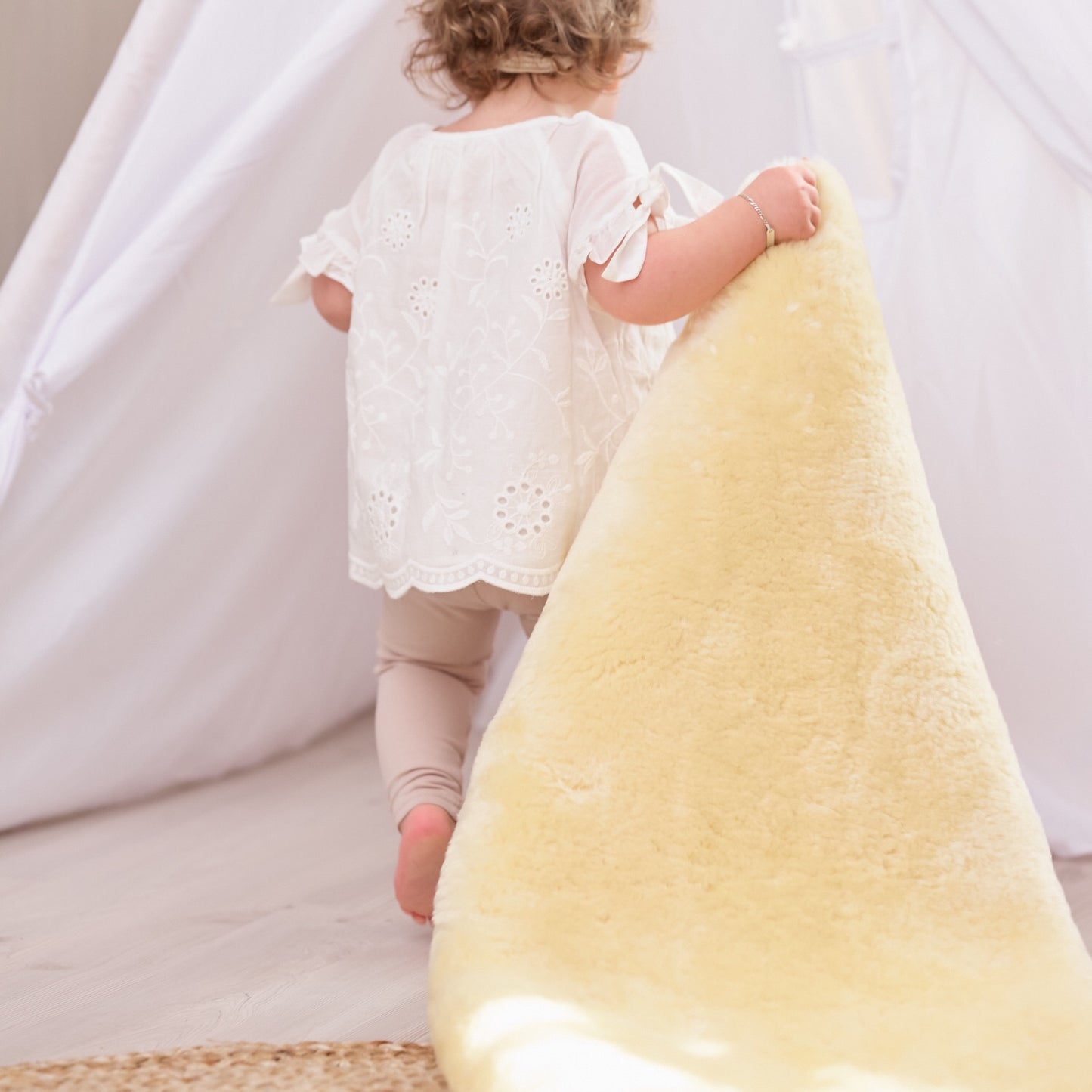 Young child carrying natural lambskin baby rug