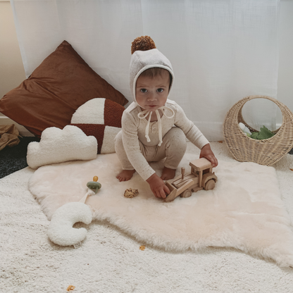 Baby boy playing on natural lambskin baby rug