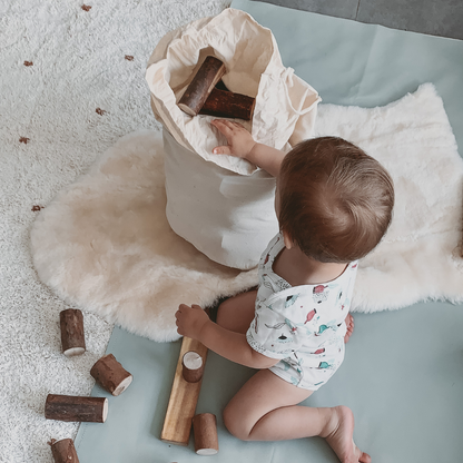 Toddler playing on natural lambskin baby rug with wooden blocks