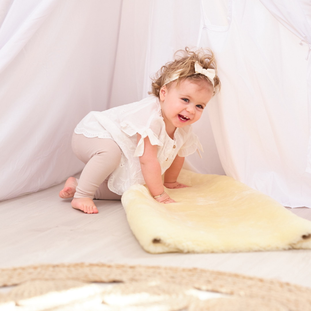 Young child playing on natural lambskin baby rug