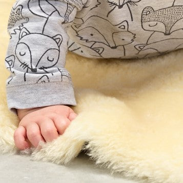 Baby's hand on natural sheepskin baby rug