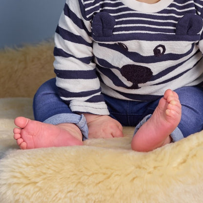 Young child sitting on natural sheepskin baby rug