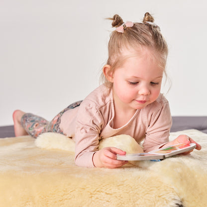 Young girl reading on genuine sheepskin baby rug